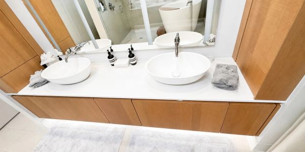 Modern bathroom with dual sinks and wooden cabinets.