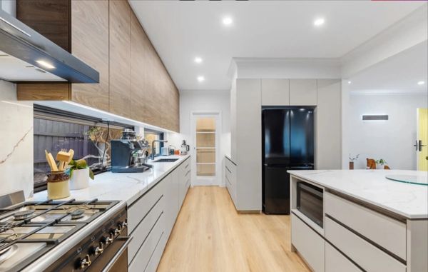 Modern kitchen with sleek cabinetry, marble countertops, and a black refrigerator.