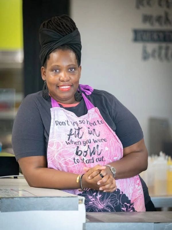 Smiling woman wearing a pink apron with an inspirational quote.