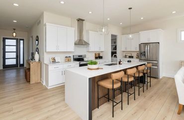Modern kitchen with white cabinets and a large waterfall quartz island.