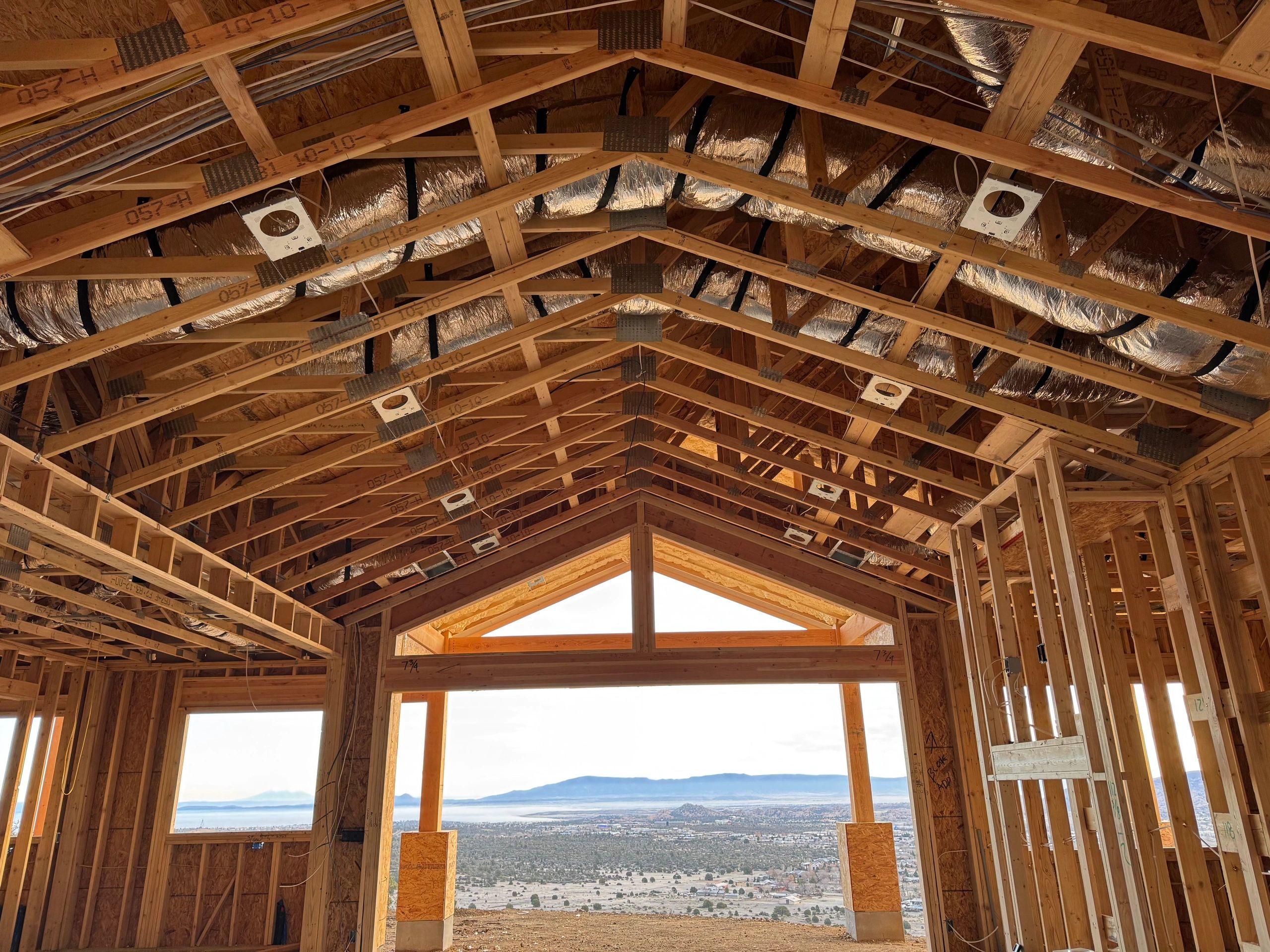 View from inside a wooden house under construction overlooking a scenic landscape.