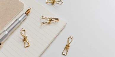 Silver fountain pen with gold nib and gold clips on a lined notebook.