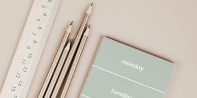 Ruler, pencils, and a weekly planner on a beige surface.