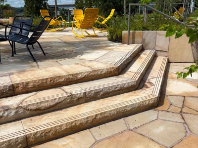 Stone steps leading to a patio with yellow and black chairs.