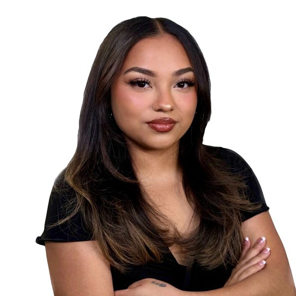 Confident woman with long hair and crossed arms against a white background.