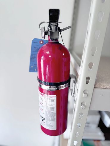 Fire extinguisher mounted the a shelving brace