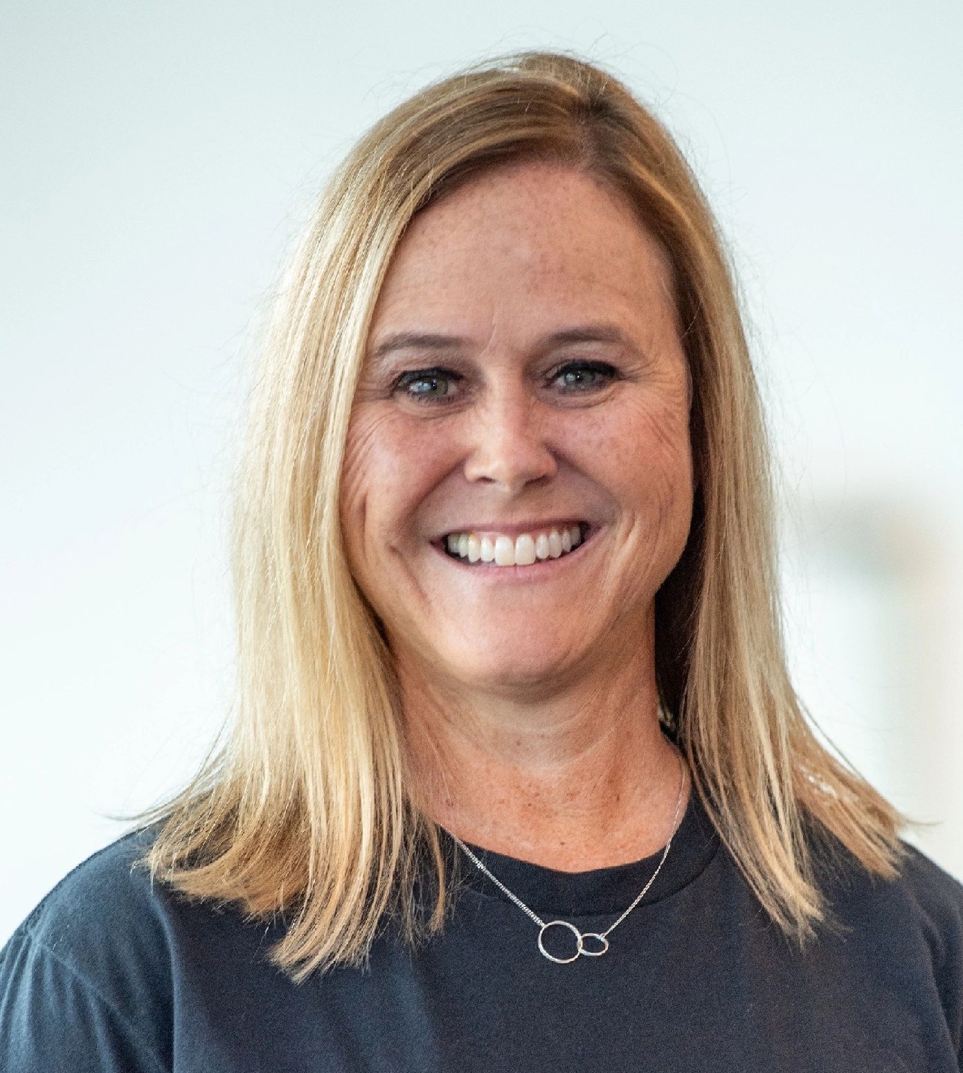 Smiling woman with blonde hair and a black shirt.