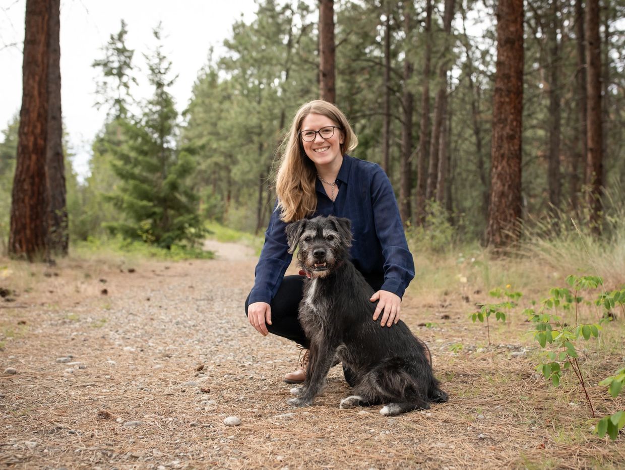 Woman smiling with her dog on a forest path.
