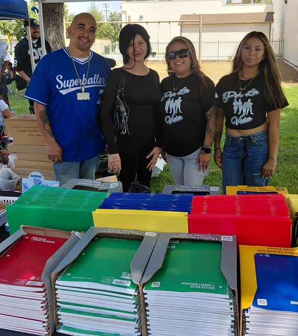 Four people standing near a table with donated school supplies.