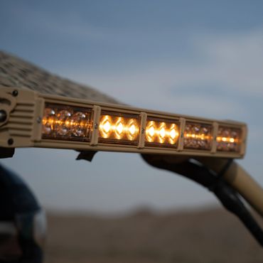 Close-up of a glowing amber LED light bar outdoors.