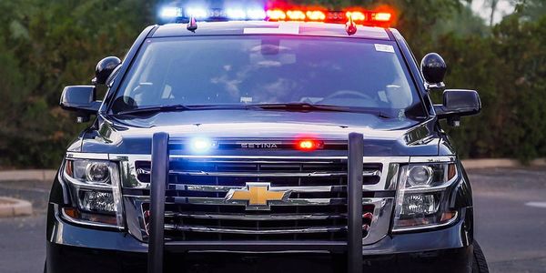 Front view of a black Chevrolet police SUV equipped with TOMAR red and blue lights.