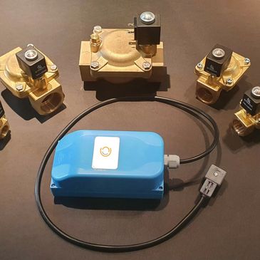 Set of brass solenoid valves with a blue electronic control module on a dark surface.