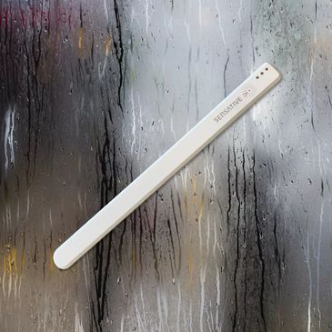White Sensative wristband on a wet glass surface with water droplets.