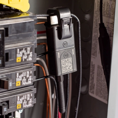 Close-up of electrical panel with connected circuit breakers and a QR-coded device.