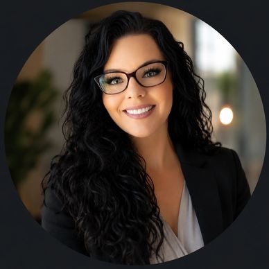 Professional woman with curly black hair and glasses smiling.