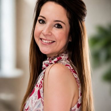 Smiling woman with long hair in a patterned sleeveless top.