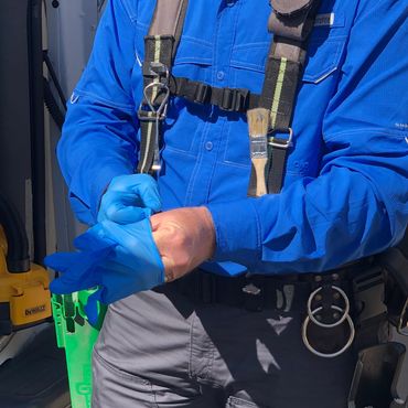 Man puts on latex gloves to prepare to clean window