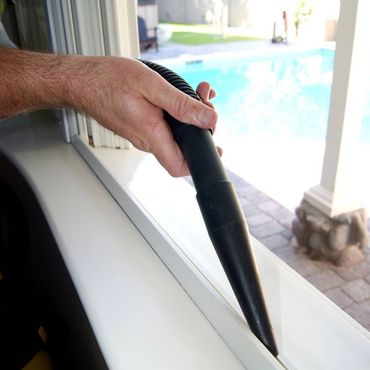 Vacuum crevice tool is being used to vacuum out a window sill track