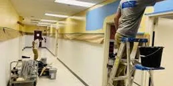People painting a hallway in a building.