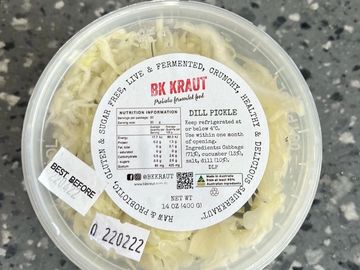 Container of BK Kraut dill pickle sauerkraut on a speckled surface.