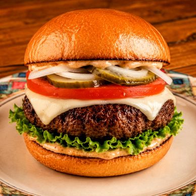 Juicy cheeseburger with American cheese, lettuce, tomato, pickles, onion, and burger sauce on a toas