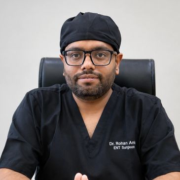 Portrait of a male ENT surgeon in black scrubs.