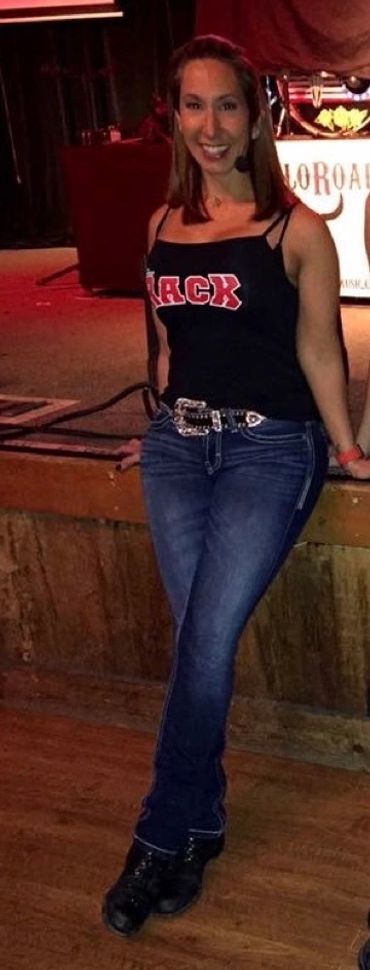 Young woman smiling indoors, dressed casually in jeans and a tank top.