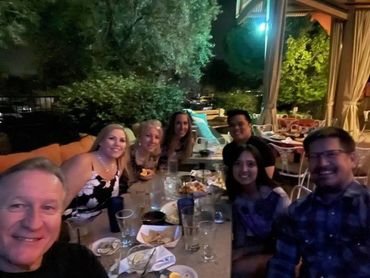 Group of friends enjoying a nighttime outdoor dinner with smiles and drinks.