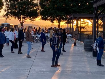 People lined up outdoors at sunset, some wearing masks and boots.