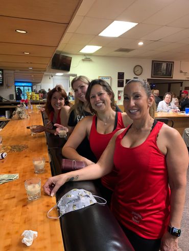 Four smiling women at a bar, holding drinks and enjoying a night out.