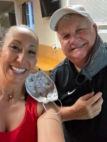 Two smiling people posing indoors, one wearing a Snoopy face mask on their arm.