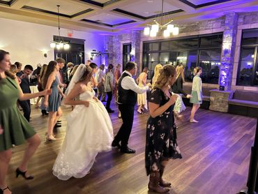 Guests including the bride dance in a warmly lit reception hall.
