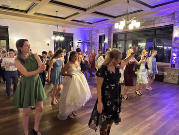 People dancing at a lively indoor wedding reception.