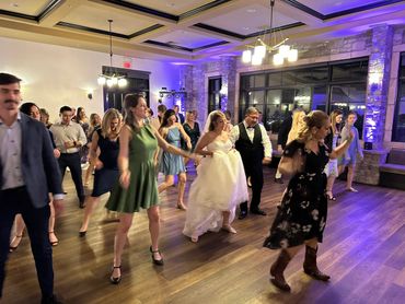 Group of people dancing at a wedding reception indoors.
