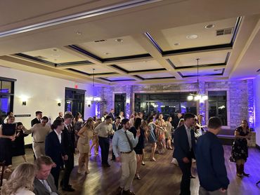 People dancing together in a well-lit indoor venue with wooden floors.