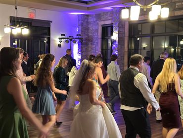 People dancing in a warmly lit room at a wedding reception.