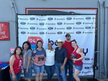 Group of seven people posing with plaques in front of a Marines and Ford banner.