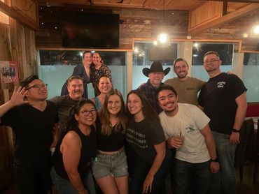 A group of friends smiling and posing together indoors at night.