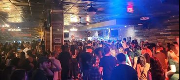 Crowded bar scene with people socializing under warm lighting.
