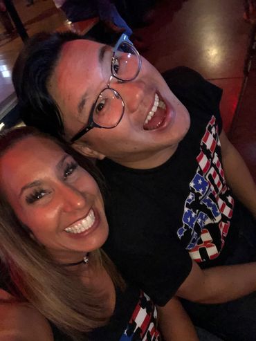 Two friends smiling widely, enjoying a lively night out.