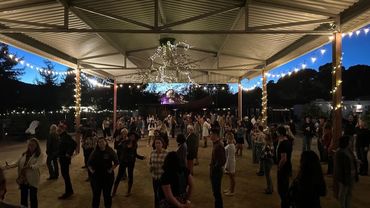 People gathered under a lit outdoor pavilion at dusk.