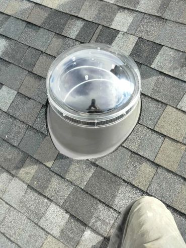 A rooftop solar tube light installed on asphalt shingles.