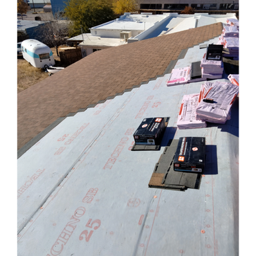Roofing materials and nails on a partially shingled roof under construction.