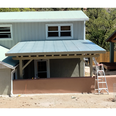 Newly constructed porch with corrugated metal roof and ladder on the side.