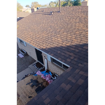 View of a house roof with construction materials piled near the entrance.