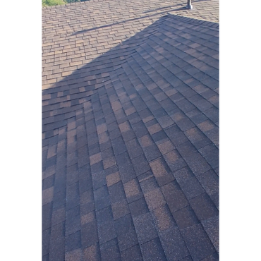 Close-up of a shingled roof with visible shadows and slight wear.