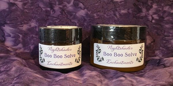 Two jars of Nightshades Boo Boo Salve on a purple cloth.