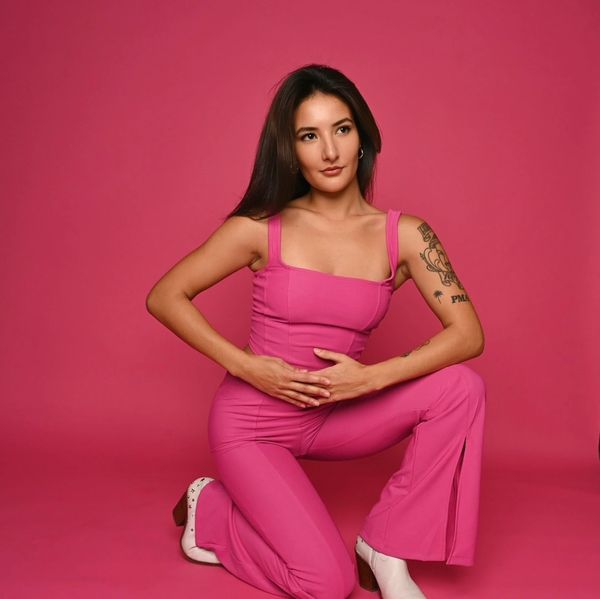 model with straight black hair , pink monochromatic outfit and backdrop . white boots 