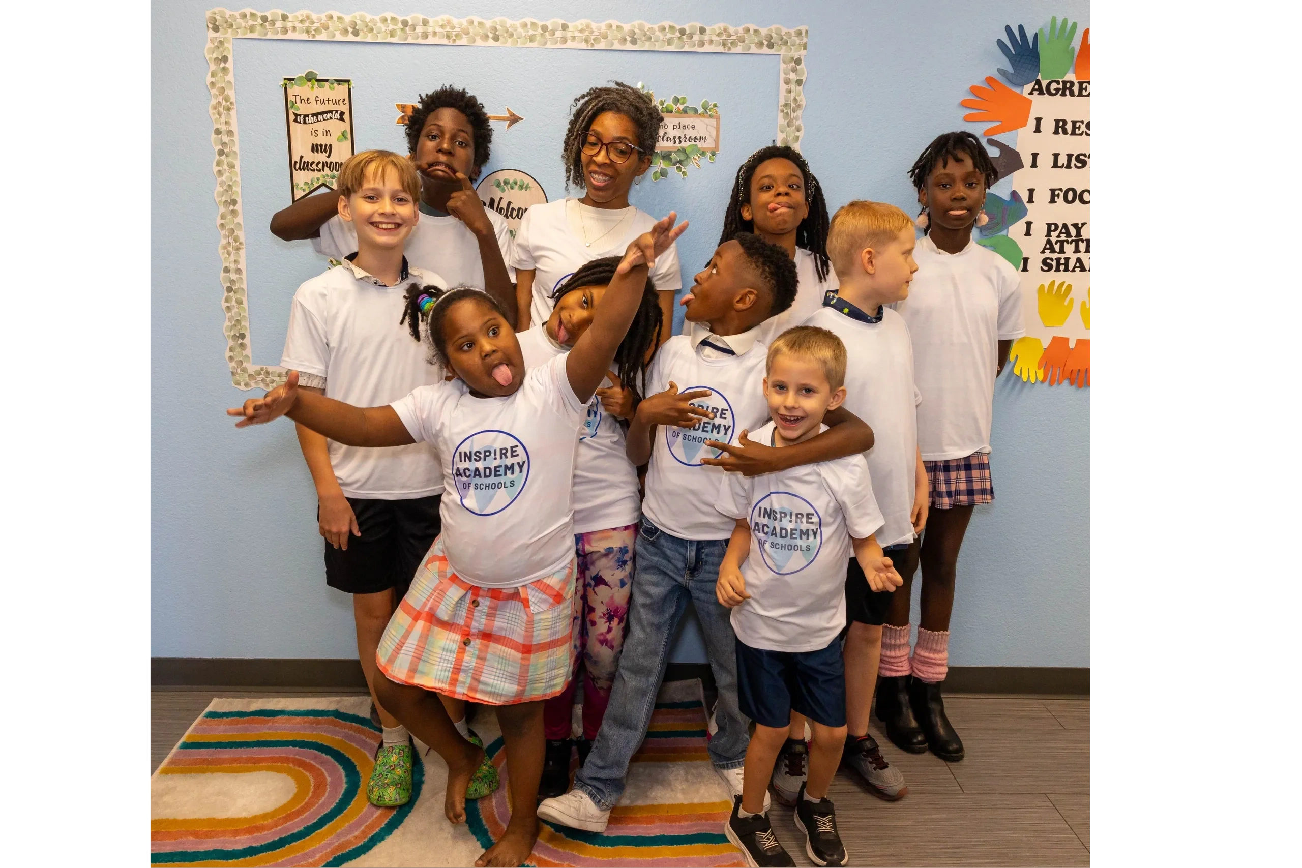 A group of playful children and a teacher posing in a colorful classroom.