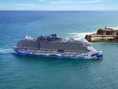Large cruise ship sailing near a coastal fort.